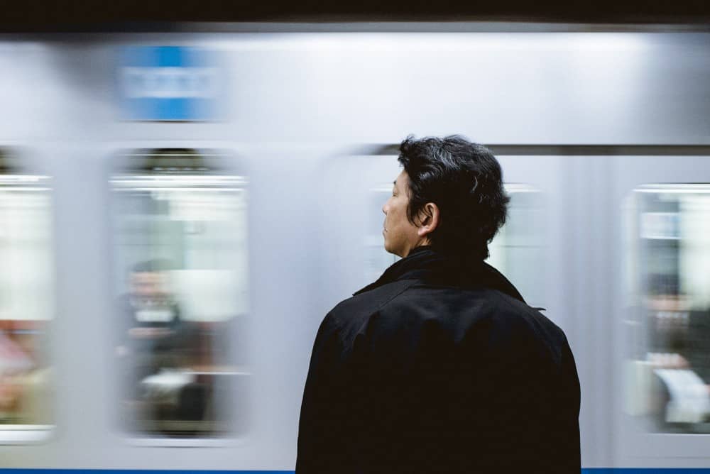 a man looking at a Japanese train going past
