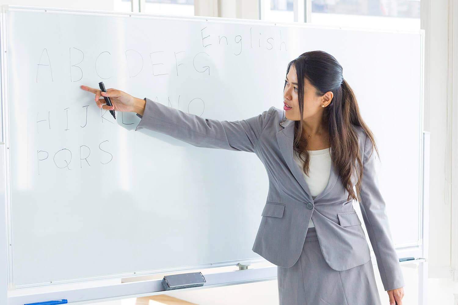 Women teacher teaching the alphabet on a whiteboard