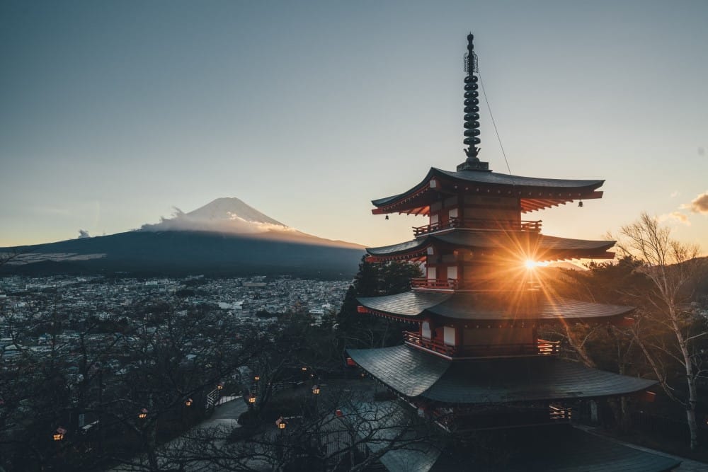 a sunrise over a city in front of Mount Fuji in Japan