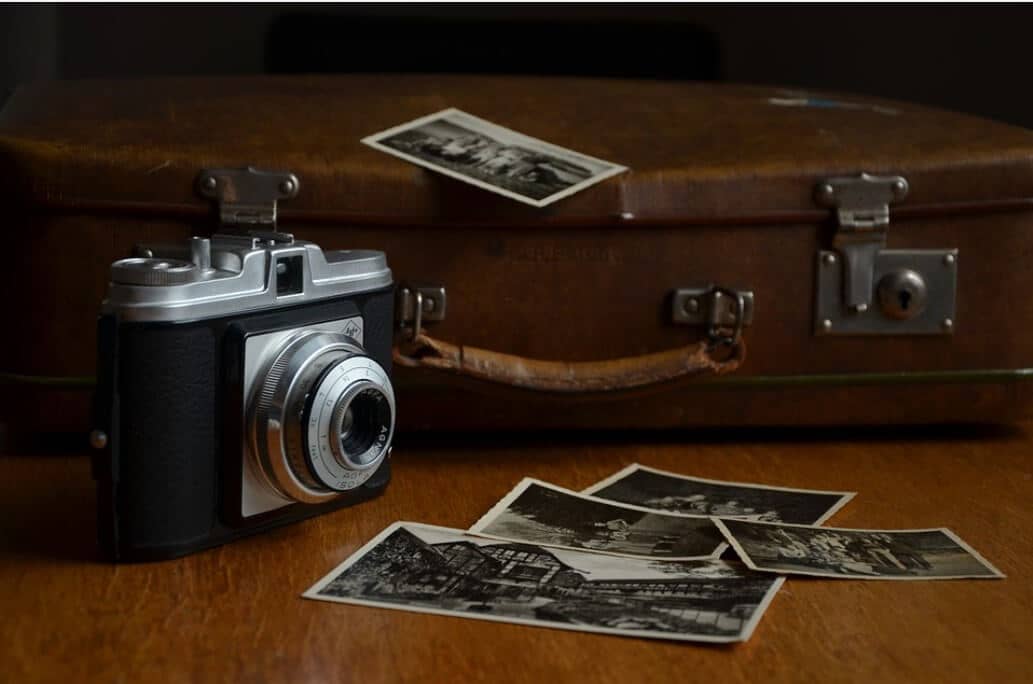 A historical luggage bag next to an old fashioned camera.