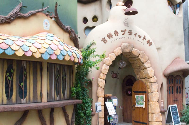 Fantasy castle style cat cafe exterior with colourful roof and large wooden open door.