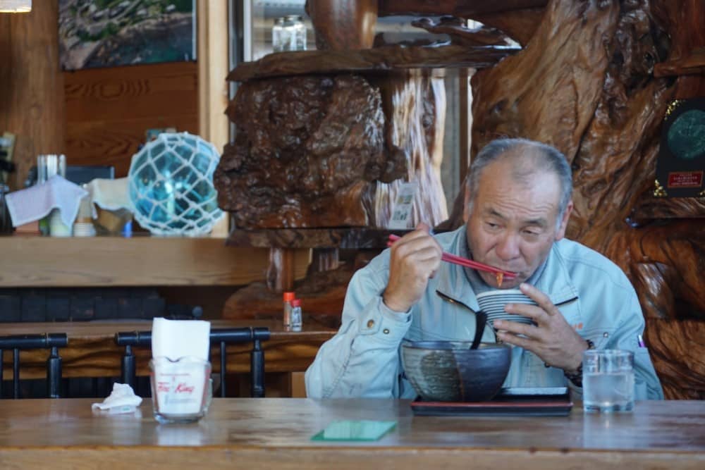 a Japanese man eating noodles with chopsticks
