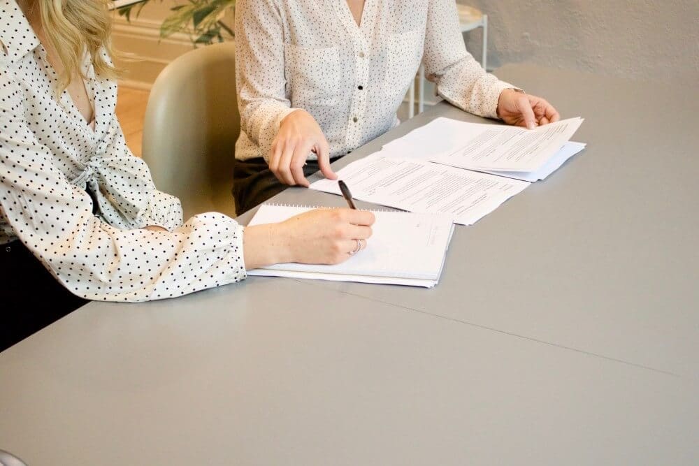 two women in blouses writing