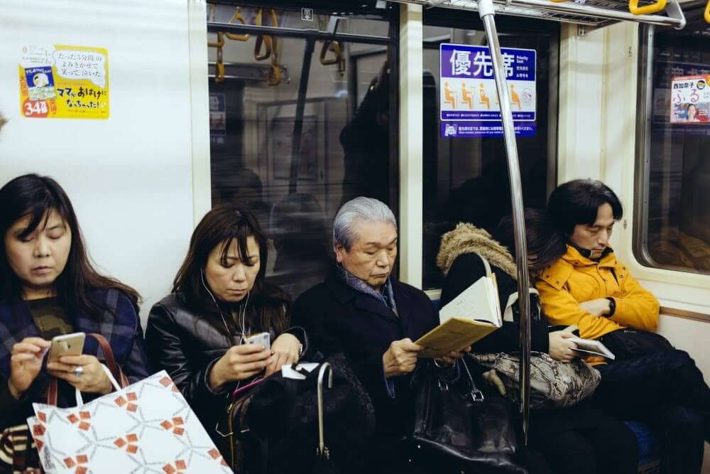 Japanese people on a subway reading phones and books