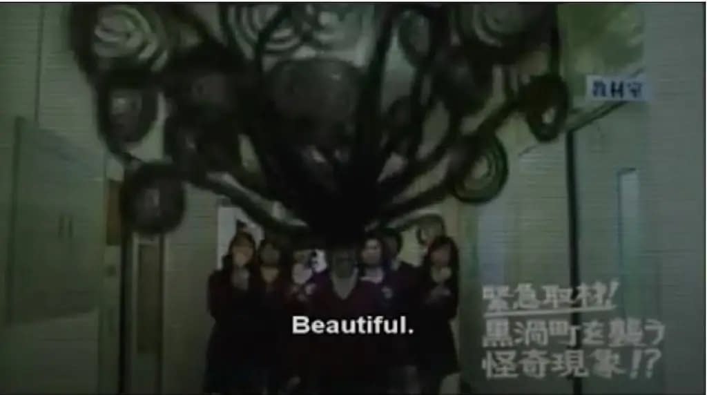 A still from the film Uzumaki, where a teenage girl walks down a school hallway with her hair in huge, looping spirals