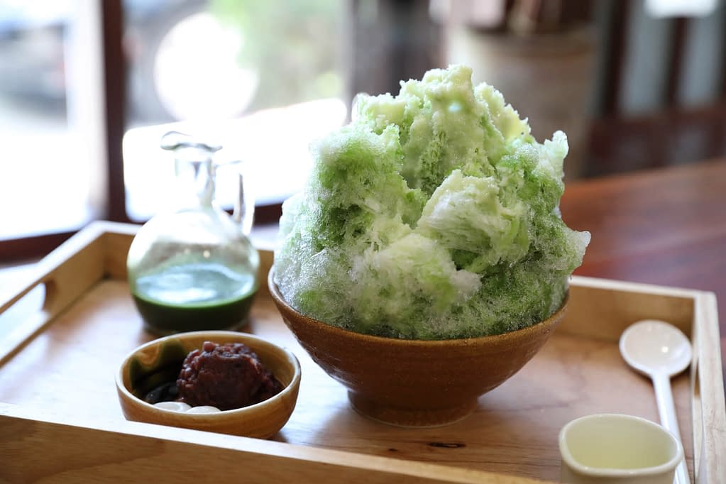 Delicious Japanese sweet shaved ice green tea on wooden table in japanese cafe
