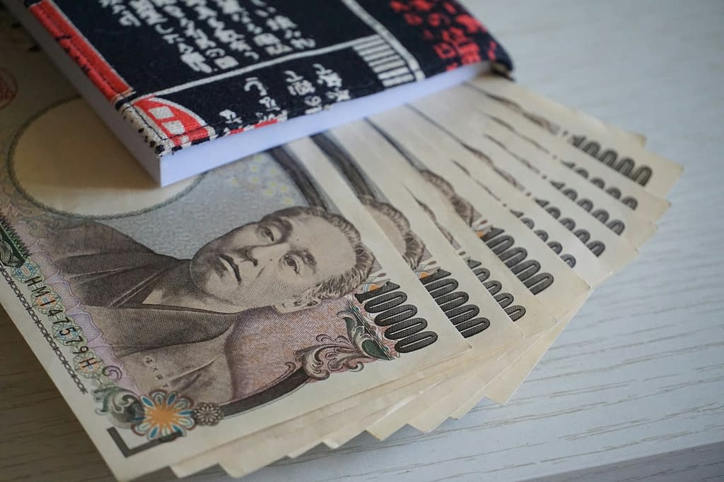 A neat pile of Japanese yen atop a notebook, illustrating the intersection of finance and academic pursuits.