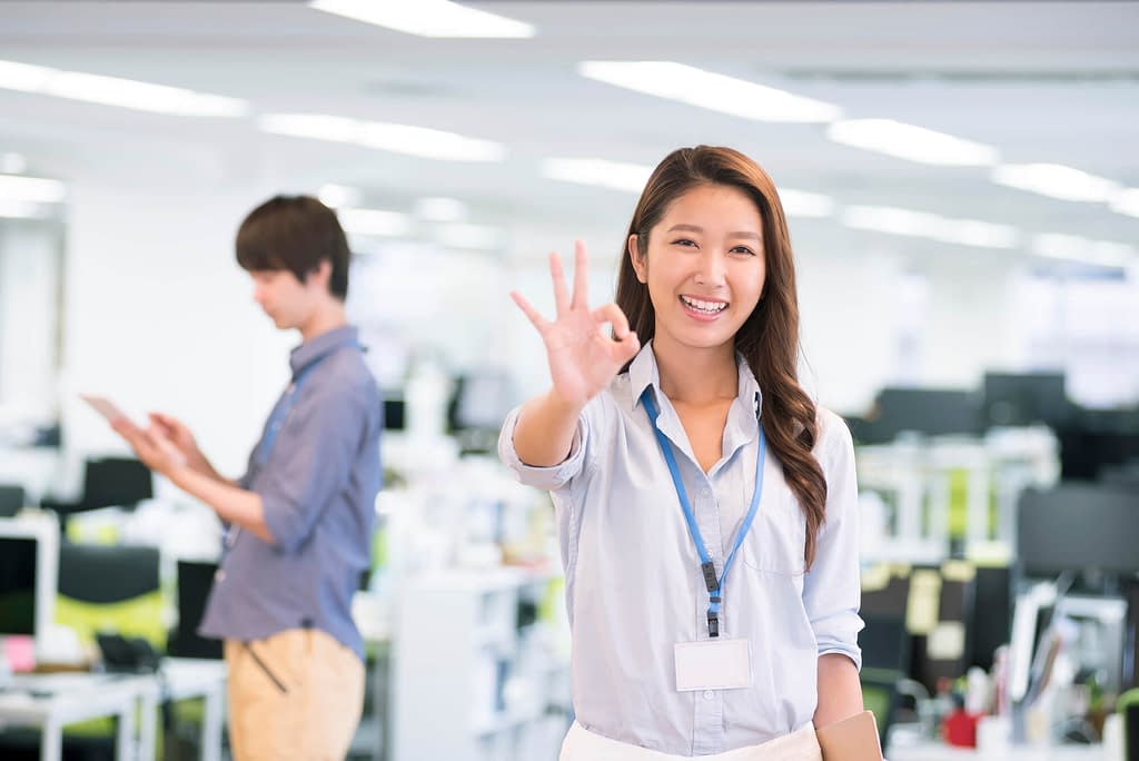 Women giving OK sign in an office