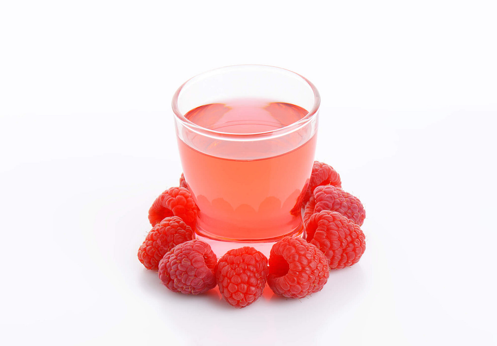 Glass of raspberry-flavored drink and fresh raspberries