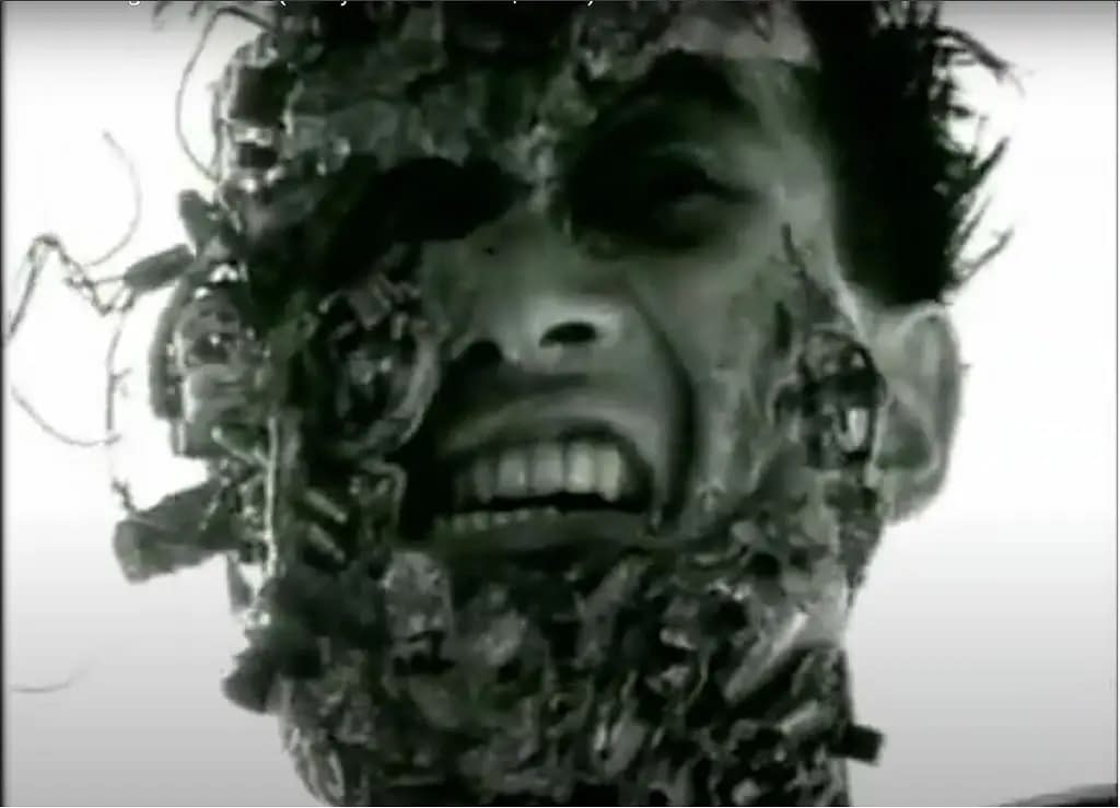 A still from Tetsuo: The Iron Man, of the protagonist's face covered in metal, which appears to rip through his skin