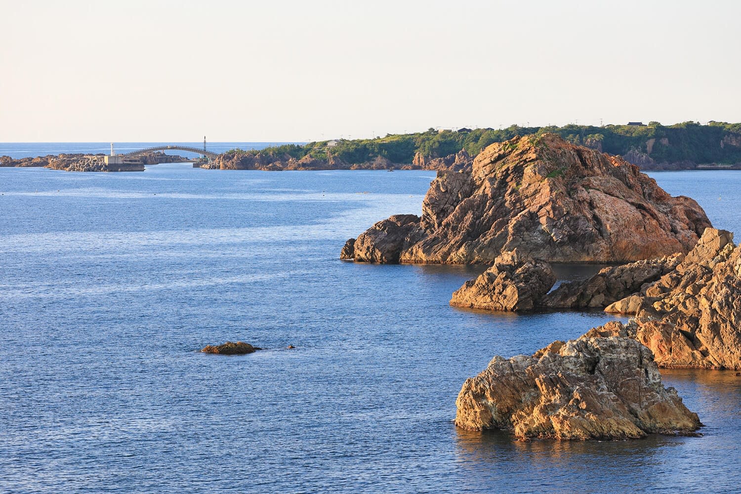 Cliffs in the ocean. Bridge linking an island to the peninsula in the background