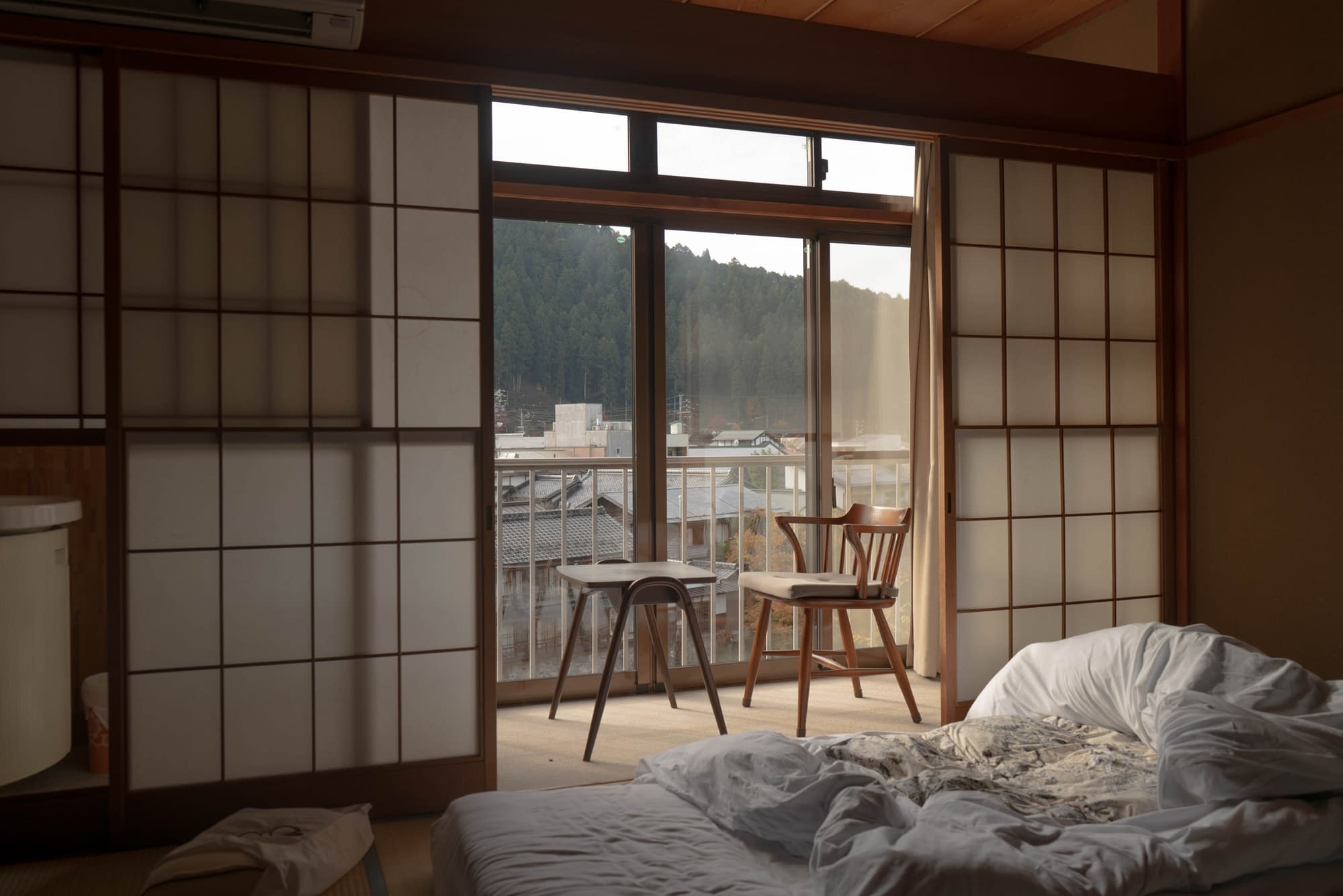 Japanese accommodation with a light, airy room. A balcony with chairs and blue sky in the background.