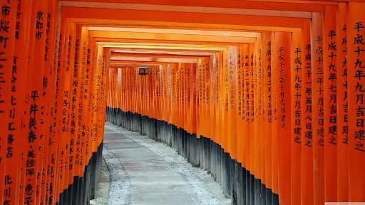 The structure of the Fushimi Inari shrine, with the orange canopy, with Japanese calligraphy painted on the posts.