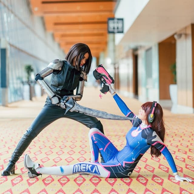 Two women pretending to battle in anime cosplay.