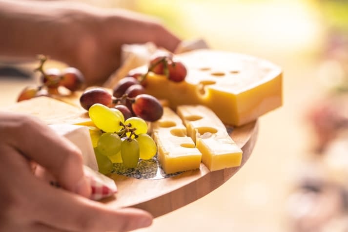 a platter of cheese and grapes being held out