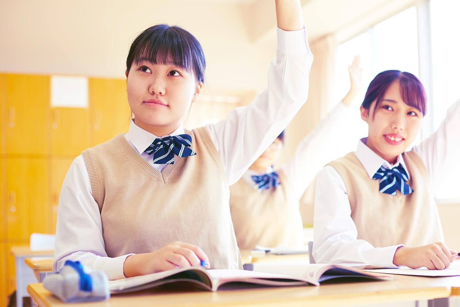Japanese students raising their hands in a classroom