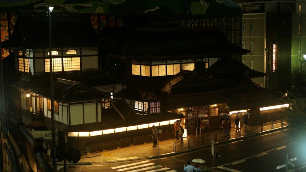 A hot bath building, softly lit from within, at night in Dogo, Japan.