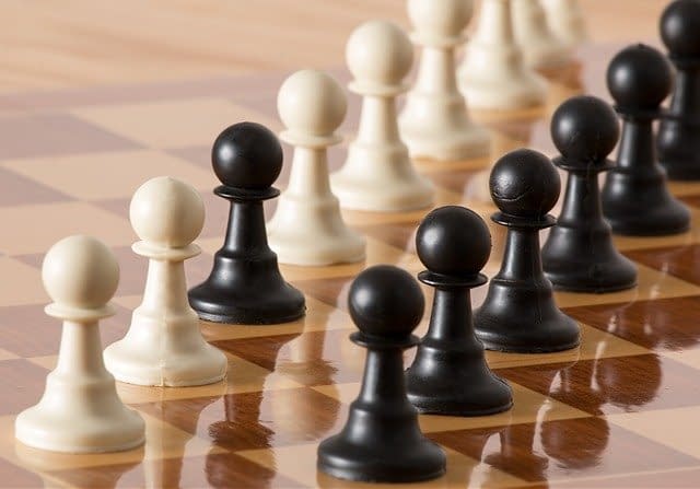 Black and white pawns lines up on a chess board.