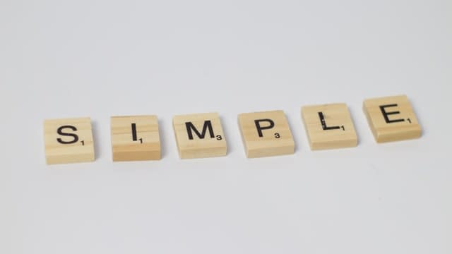 Small square wooden cut outs with letters on them that spell the word simple.