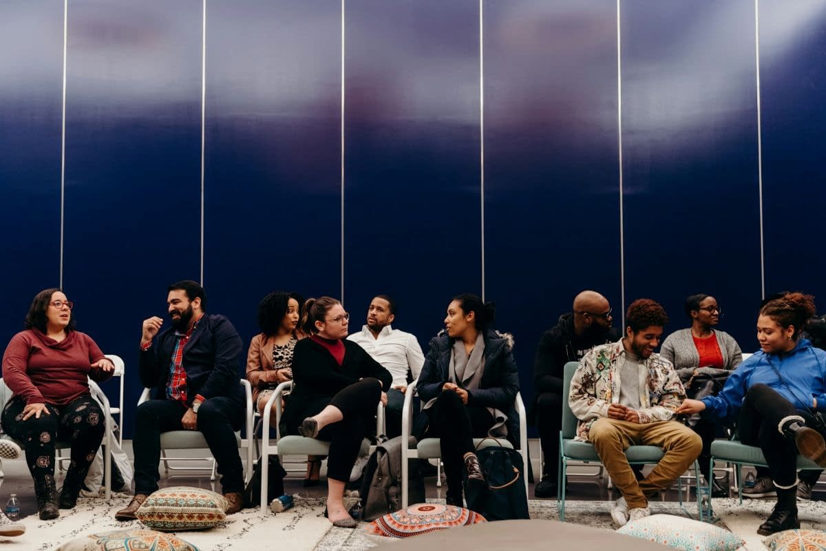 a diverse group of people sitting and talking in a room