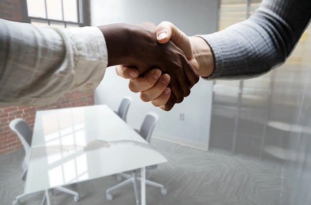 Two people shaking hands after an interview in an office.