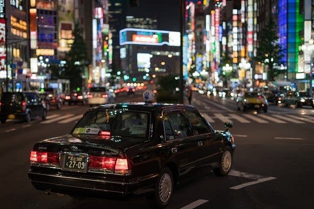 A black Japanese taxi driving through busy Tokyo streets