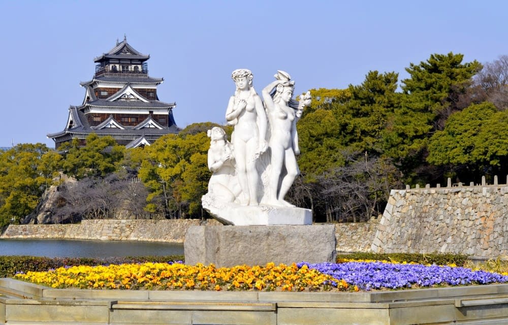 a statue in a Hiroshima park with castle in background