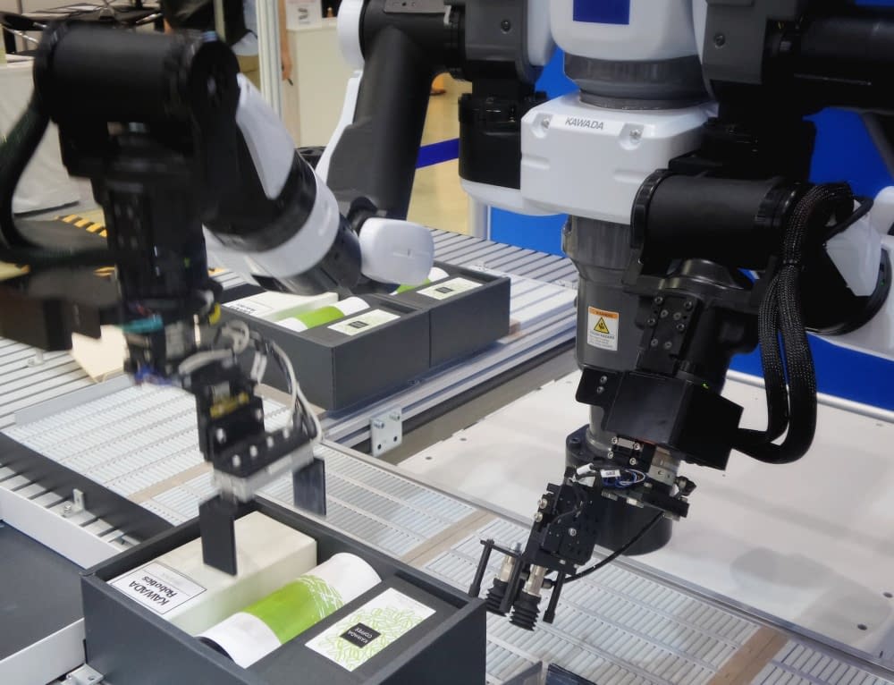 Robot arms work on a production line, packaging products.
