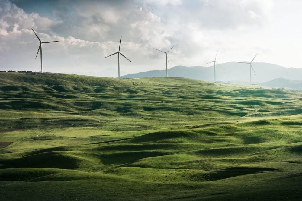 a green hill covered in wind turbines