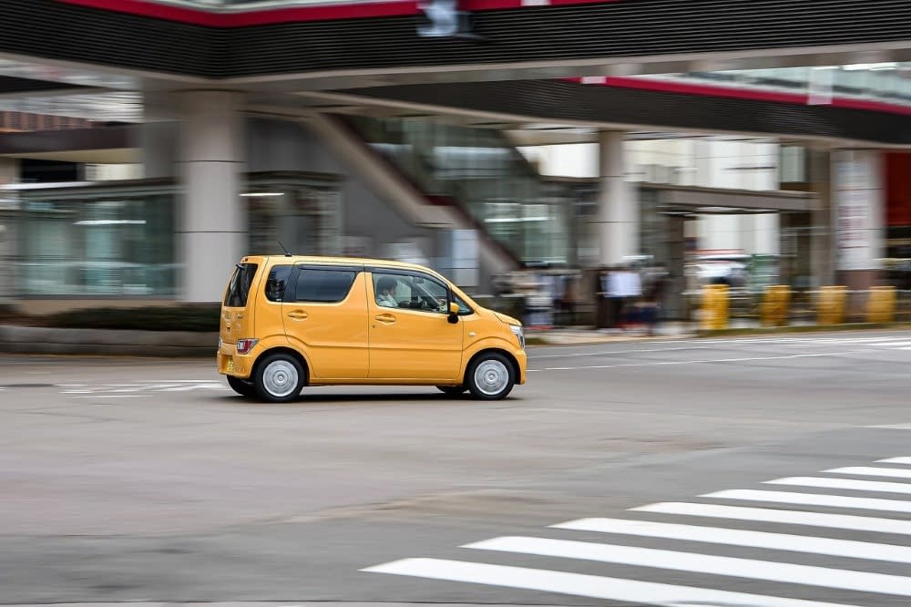yellow japanese k car driving on a street