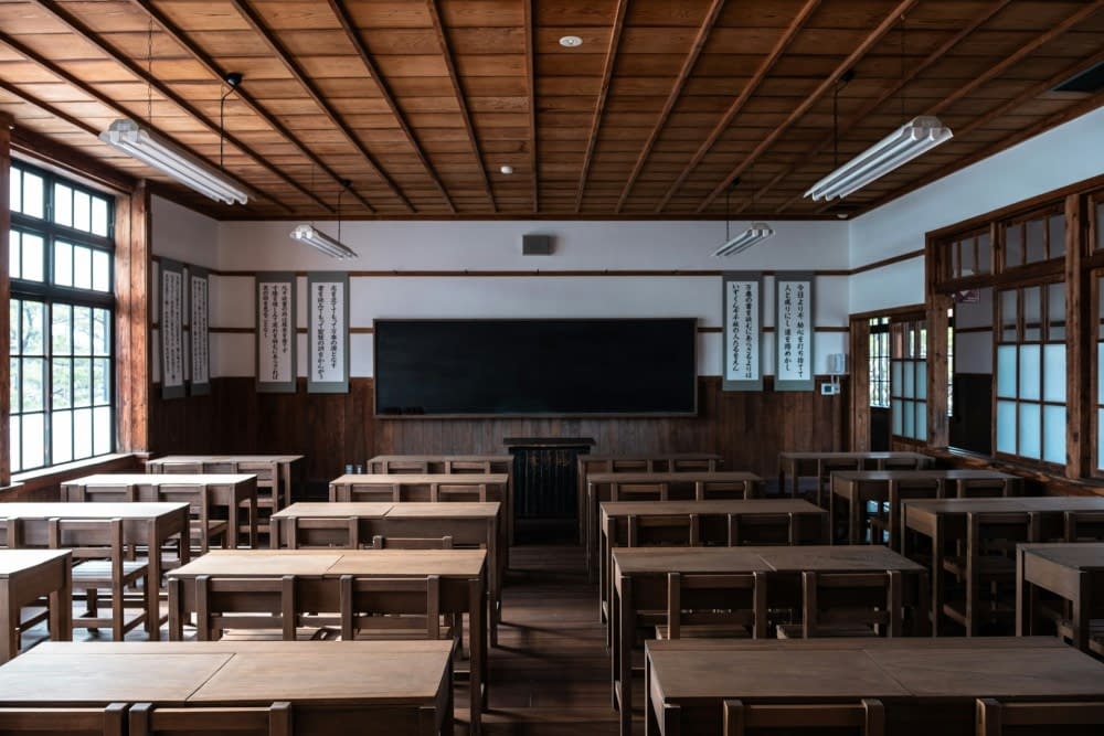 A serene Japanese classroom with wooden desks and a blackboard, waiting for students.