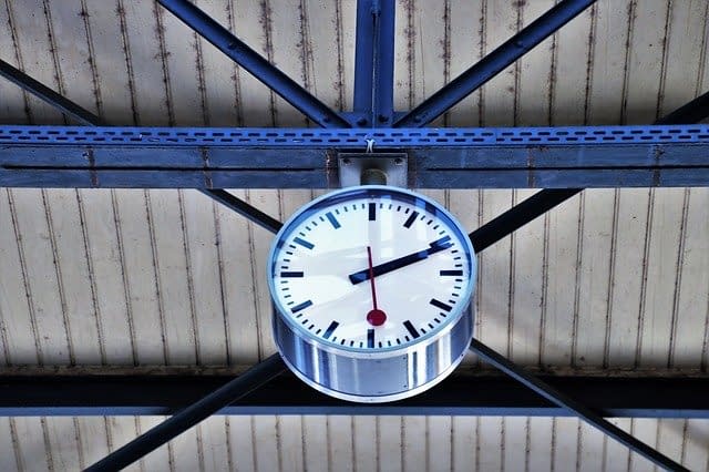 A railway station clock hanging from the ceiling