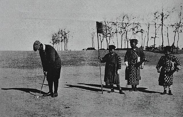 A black and white photo of people playing golf at Tokyo Golf Club in the early 1900s