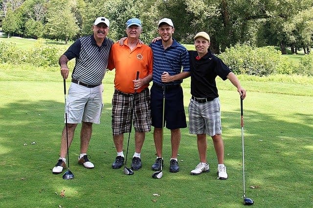 Four men on a golf course in the correct attire.