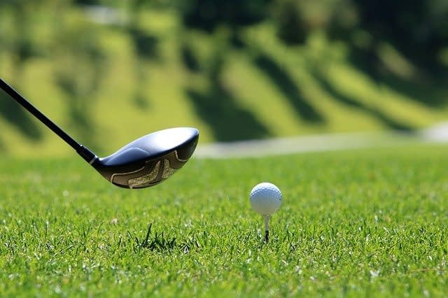 A golf club about to strike a golf ball.