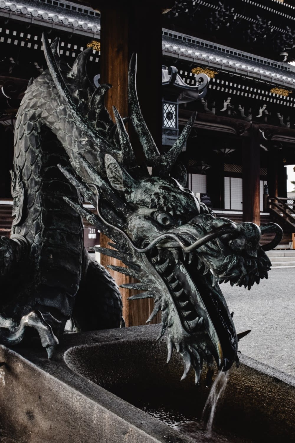 a statue of a dragon with a traditional japanese building in the background
